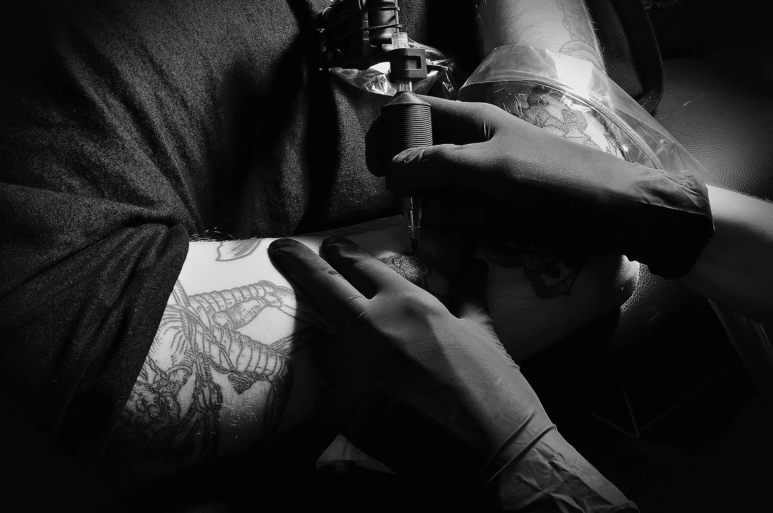 Close-up of a tattoo artist tattooing a guest's arm